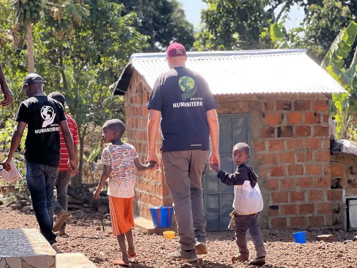 Membres du collectif avec des enfants devant un abri en briques.