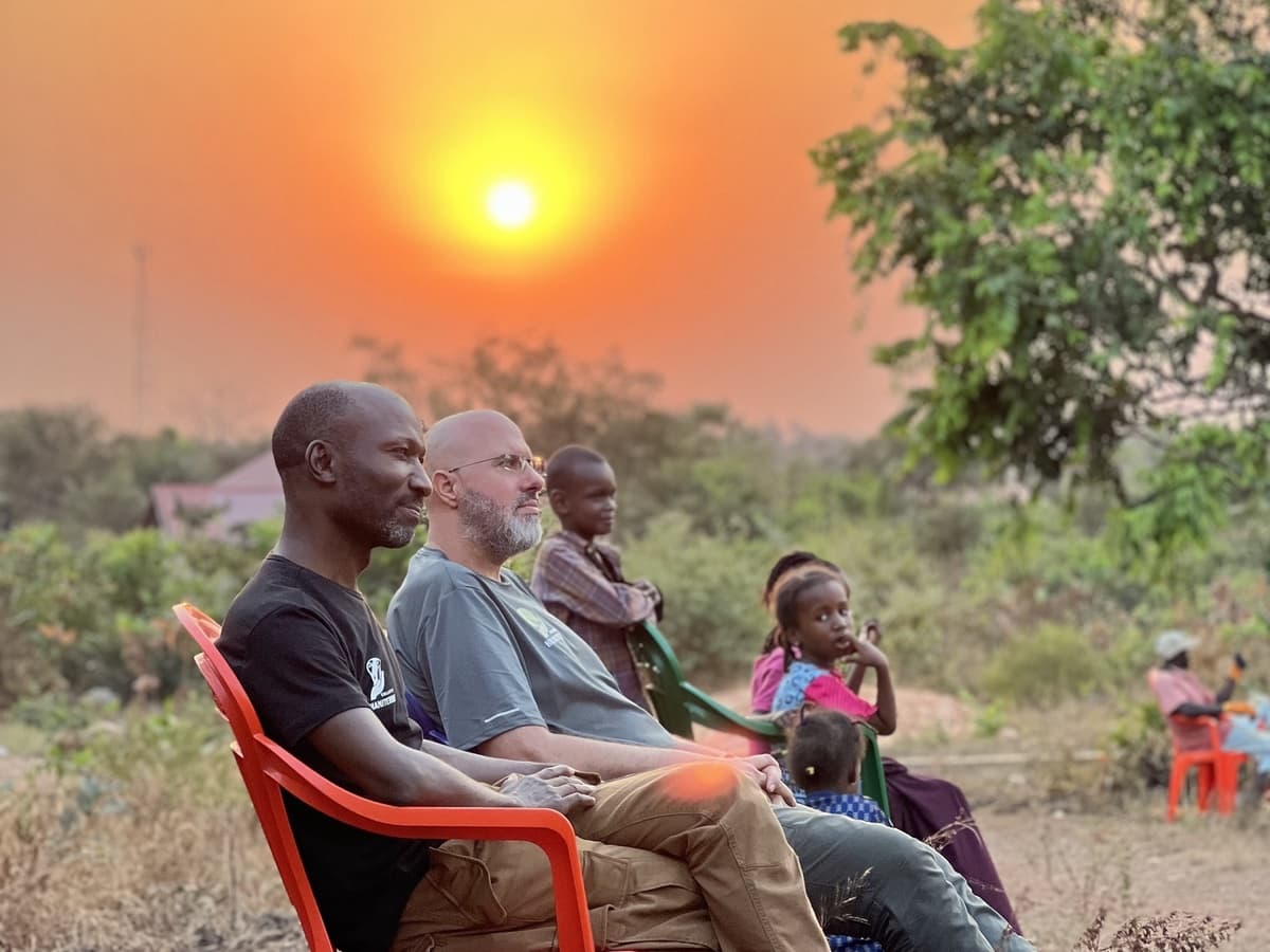 Membres du collectif assis avec des enfants au coucher du soleil.